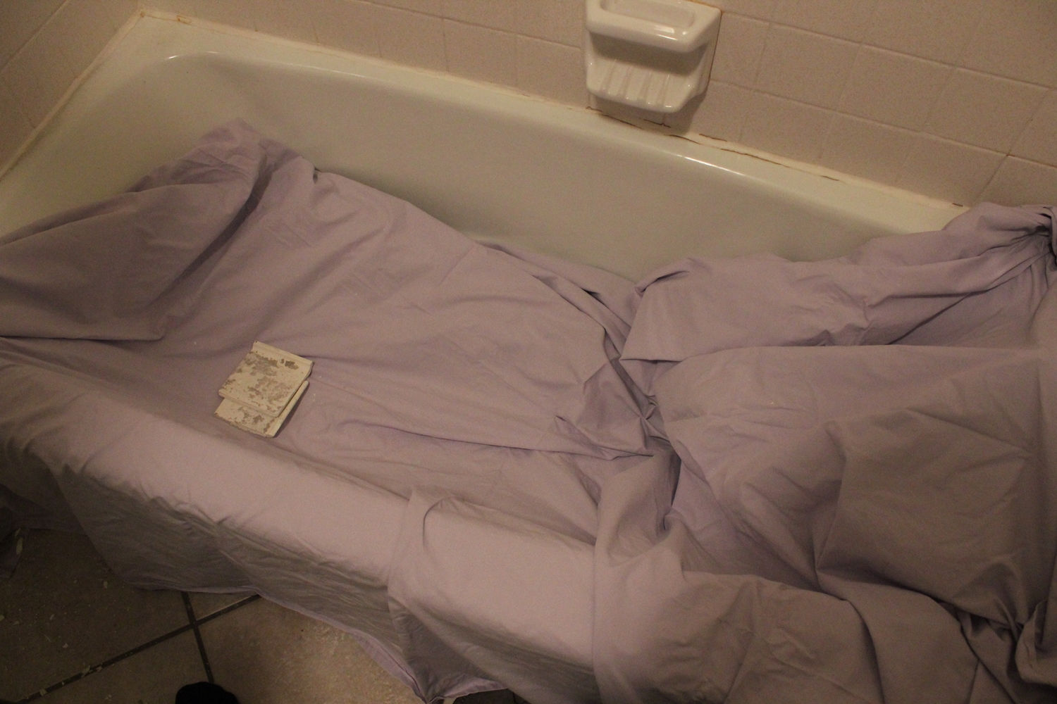 Lay an old drop cloth or sheet in the tub itself