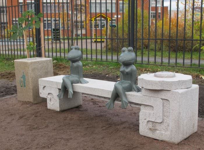 Фигурки лягушек, сидящих на декоративной скамейке